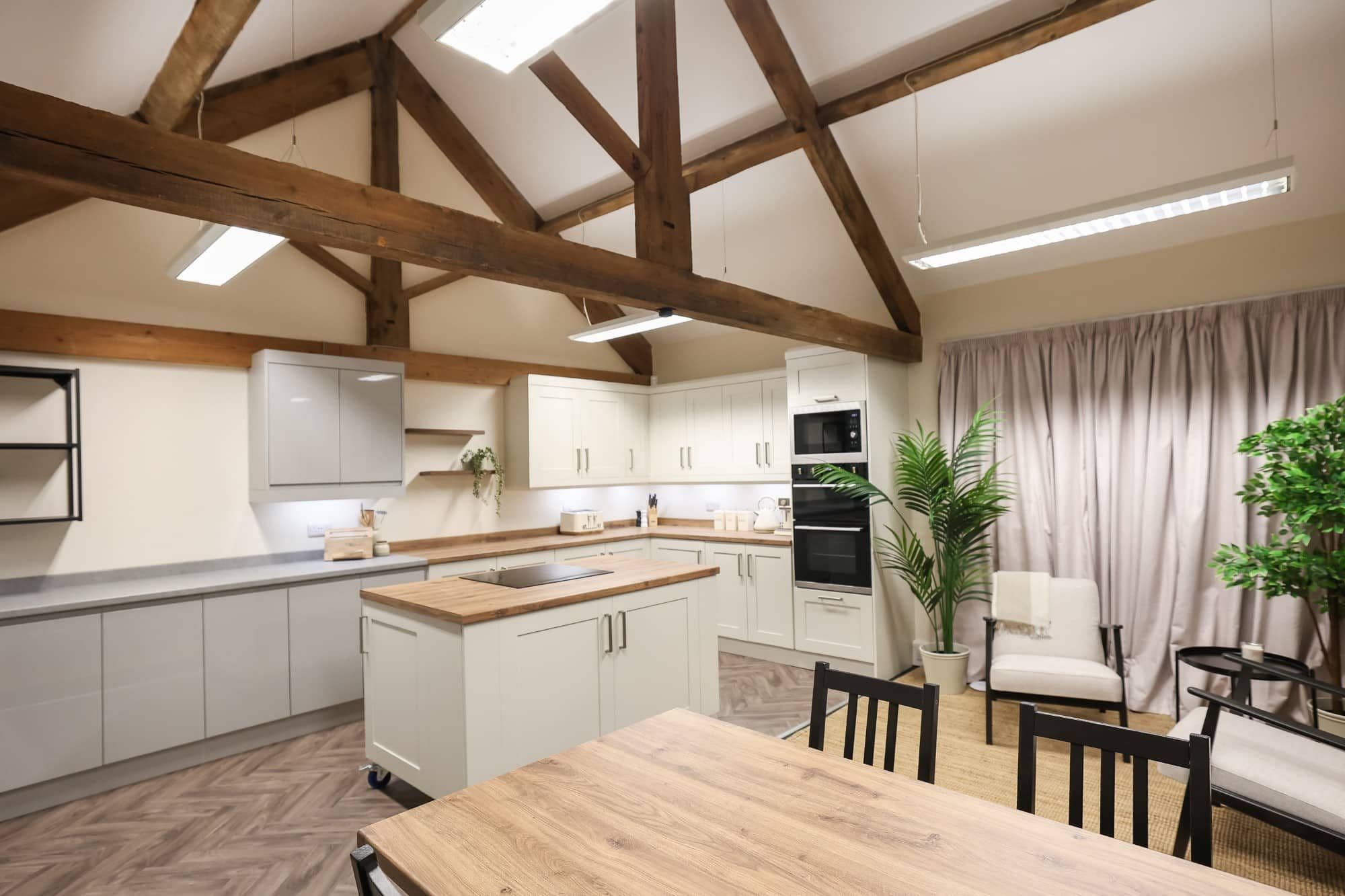 The studio's kitchen set under exposed roof beams, with an island and dining table