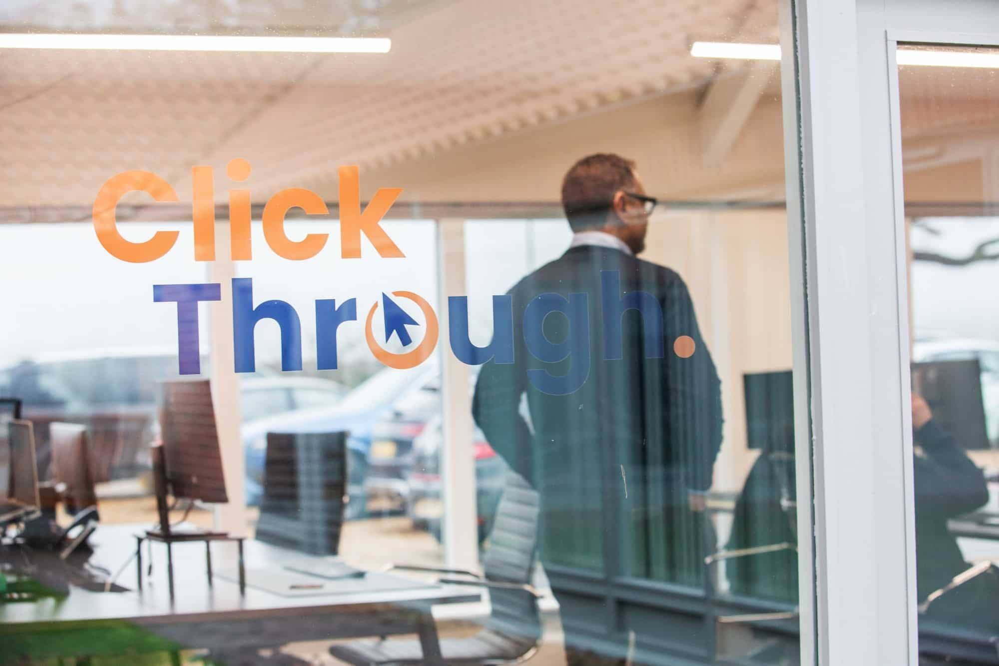 The Click Through logo on a glass office door, with a man walking inside